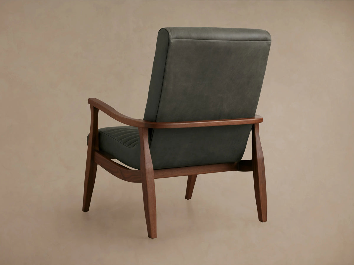 Nathaniel Leather Chair with a ribbed backrest in dark gray leather, featuring smooth wooden armrests. The chair is set against a neutral background.