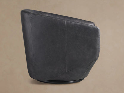 Close-up of Pelton Leather Swivel Chair's dark grey distressed leather seat, curved arm, and back with visible stitching.