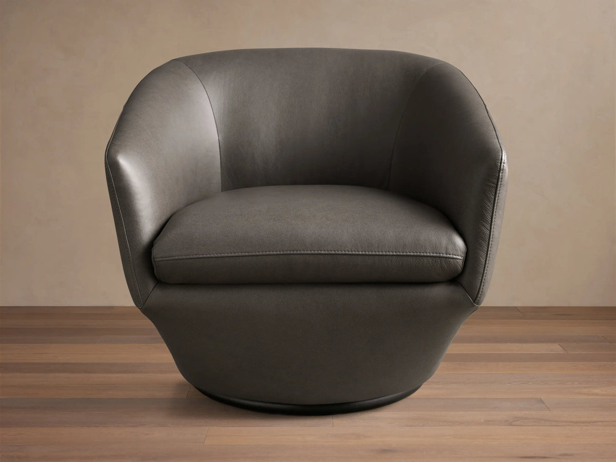 Front-side view of the dark gray Pelton Leather Swivel Chair, showing its rounded shape, deep seat, and dark swivel base.
