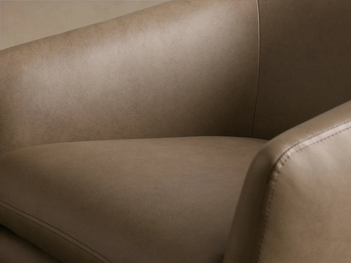 Front view of the light brown leather Pelton Leather Swivel Chair with a curved back, separate cushion, and black swivel base.
