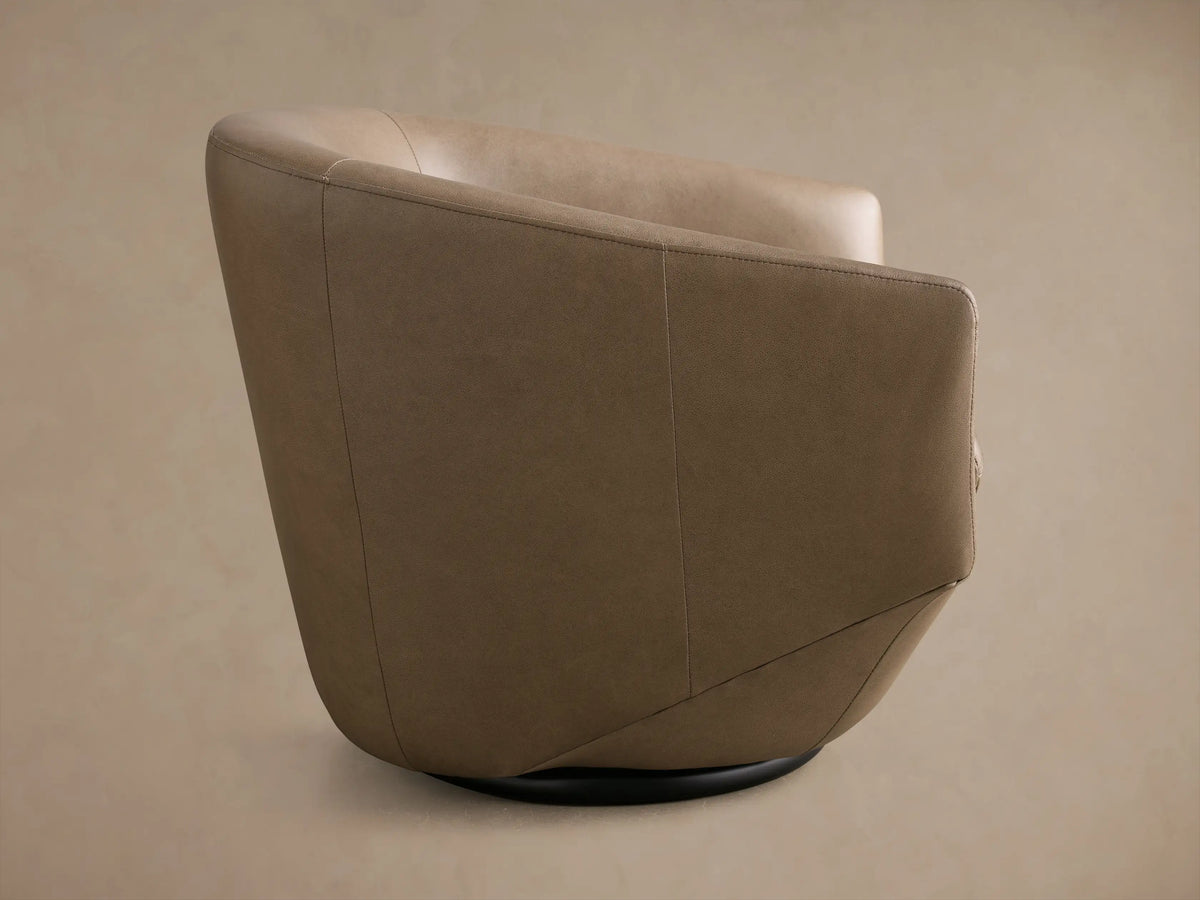 Side view of the Taupe Pelton Leather Swivel Chair, showing its curved back, visible stitching, and dark swivel base.