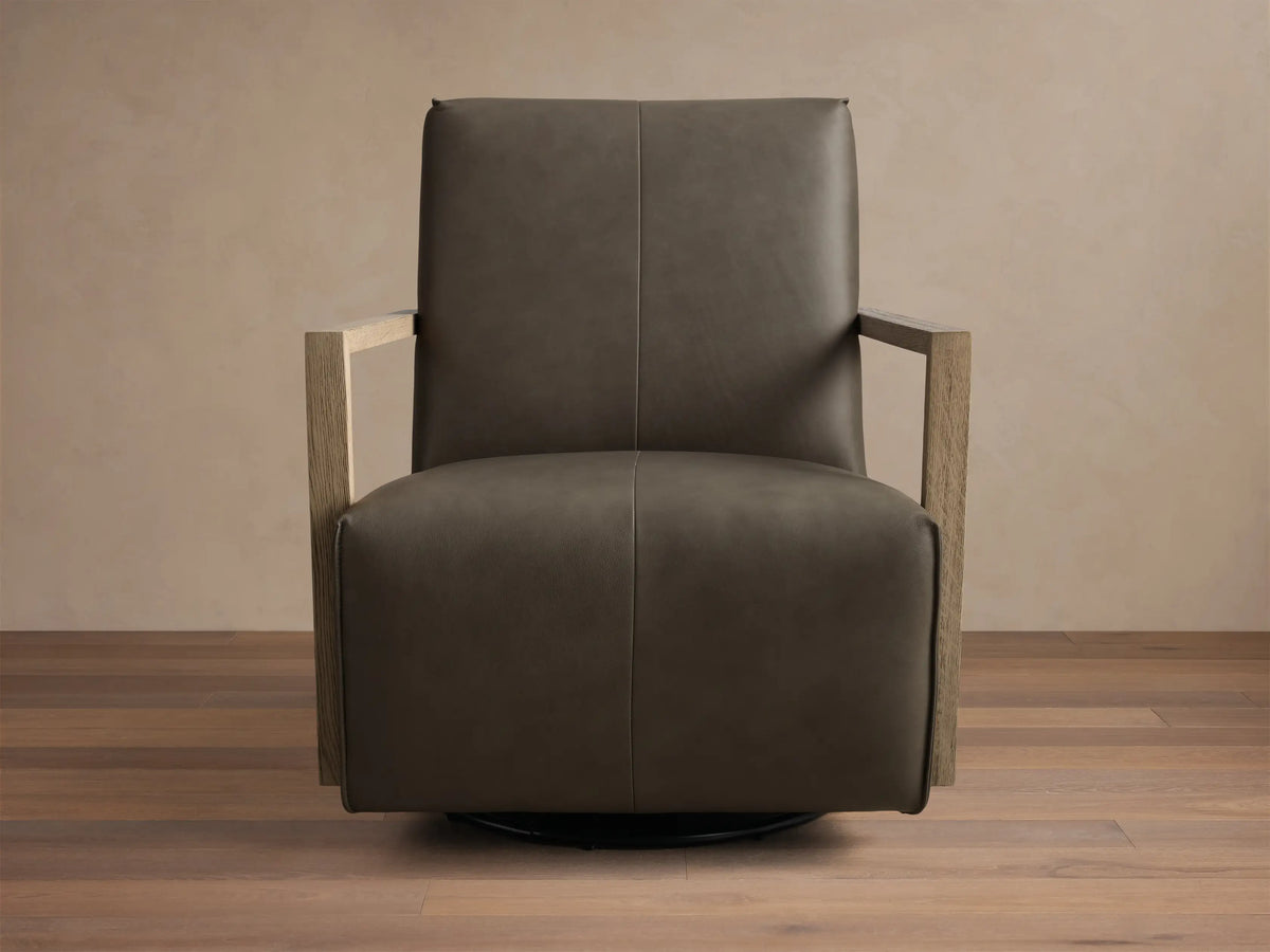 Angled front view of a dark taupe Walsh Leather Swivel Glider with light wooden armrests and a black swivel base.