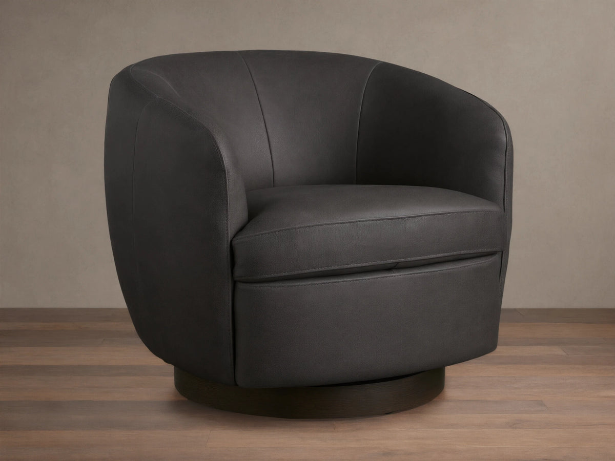 Dark grey Cerrito Leather Swivel Chair with curved back and padded seat cushion on a wooden swivel base, set on a wooden floor.