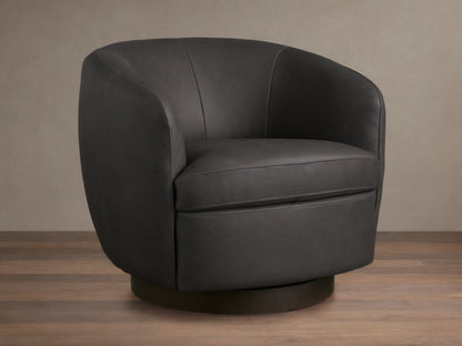 Dark grey Cerrito Leather Swivel Chair with curved back and padded seat cushion on a wooden swivel base, set on a wooden floor.