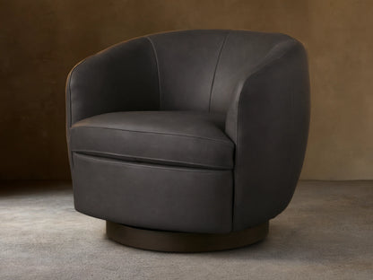 Dark grey Cerrito Leather Swivel Chair with curved back and padded seat cushion on a wooden swivel base, set on a wooden floor.