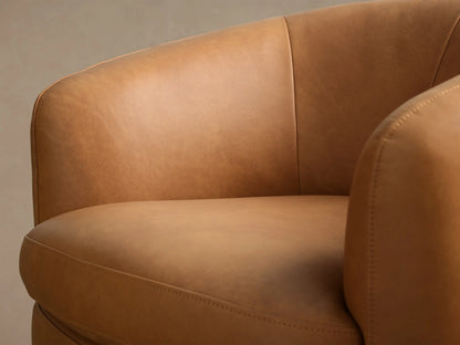 Close-up of the tan leather Cerrito Leather Swivel Chair, showing curved backrest, armrest, and seat with stitching.