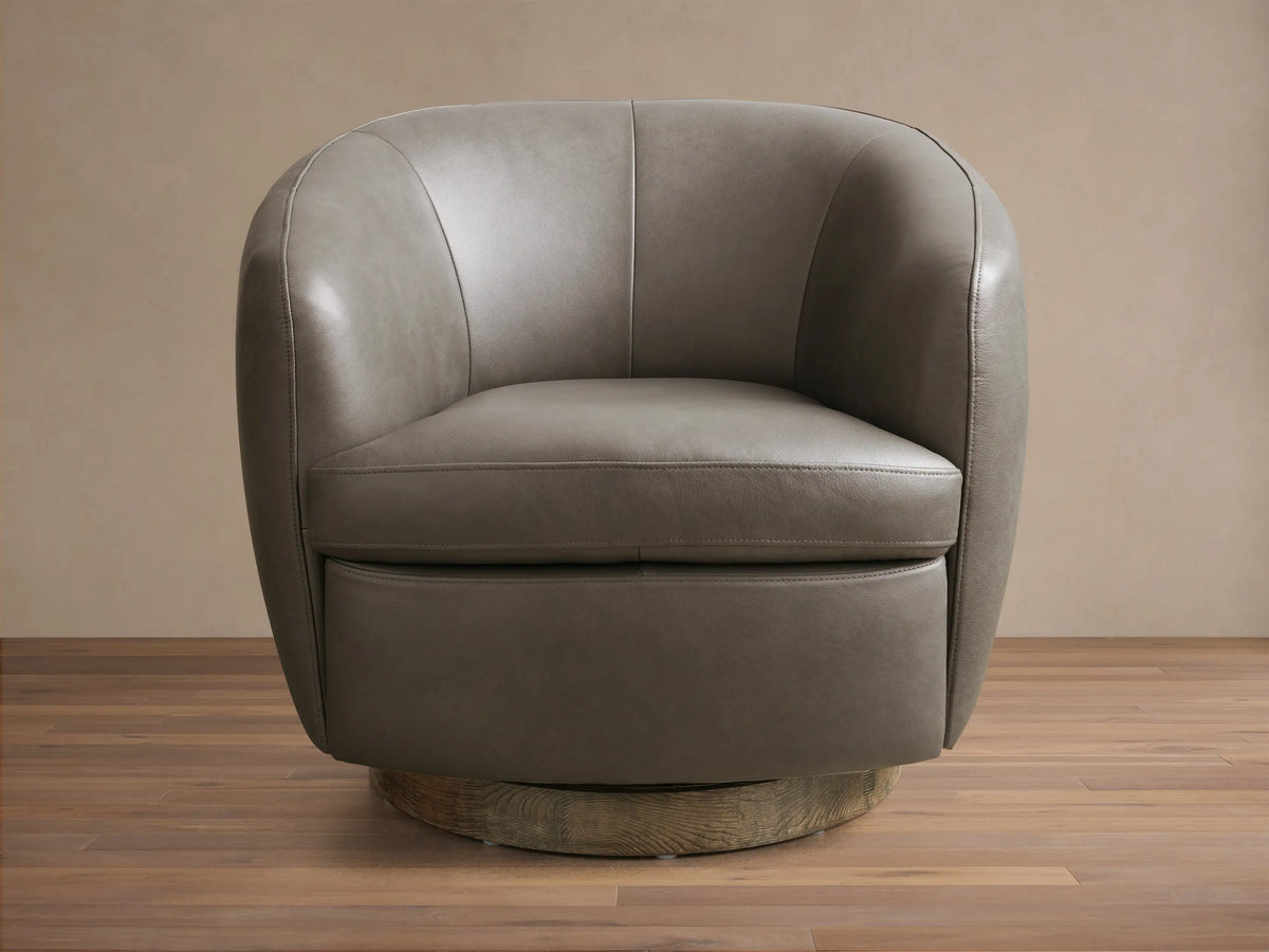 Front view of the taupe Cerrito Leather Swivel Chair, featuring curved arms and back, with a round wooden swivel base.
