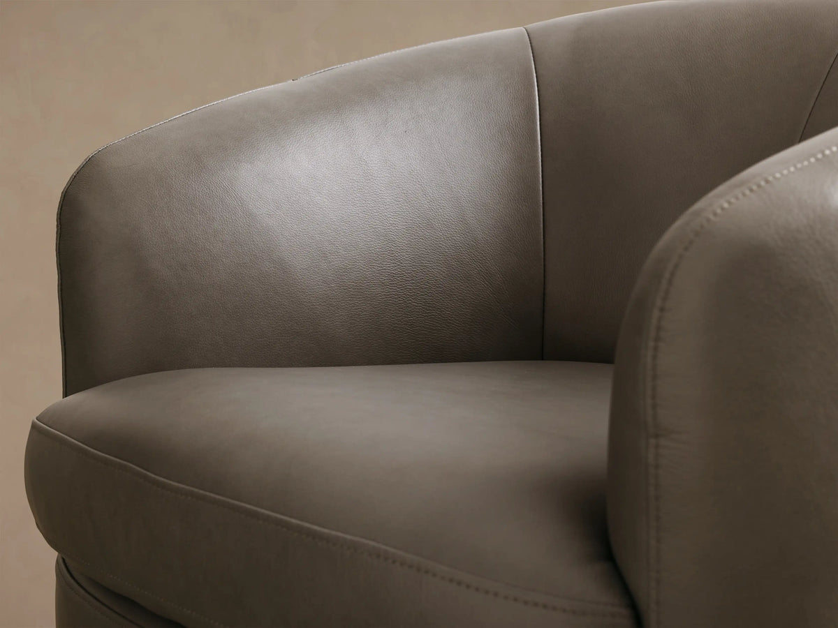Close-up of the taupe leather Cerrito Leather Swivel Chair, showing the curved armrest and seat with visible stitching.