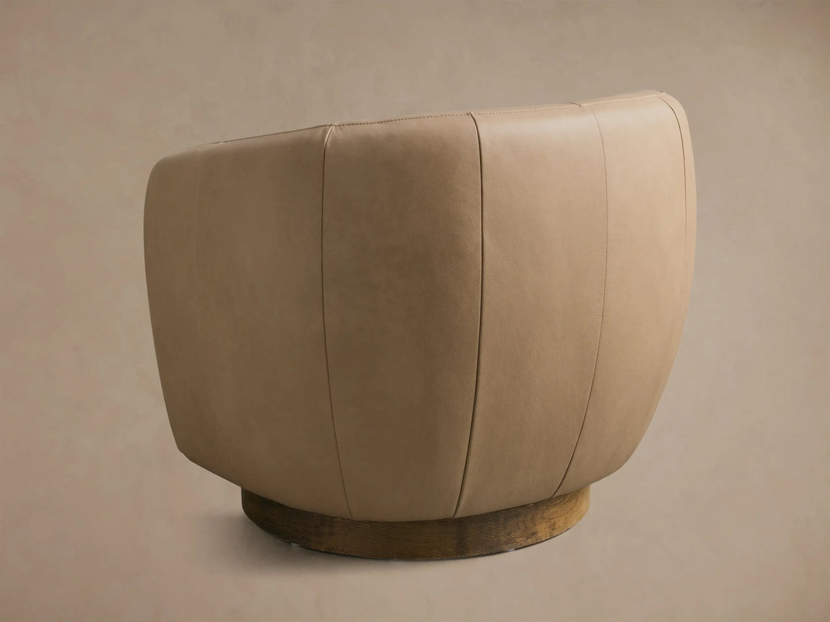 Rear view of the light tan Cerrito Leather Swivel Chair, featuring vertical panel stitching and a dark wooden swivel base.