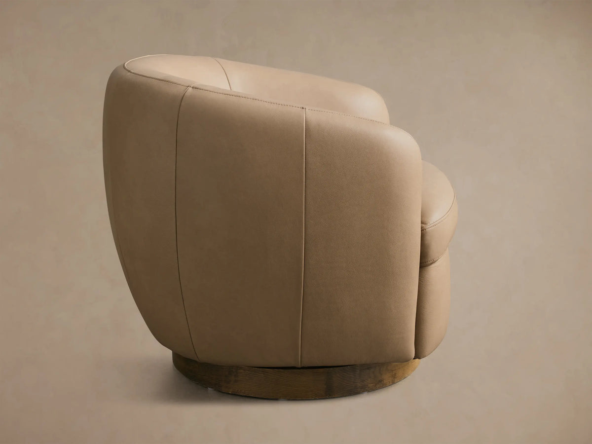 Side profile of the light brown leather Cerrito Leather Swivel Chair, showing its rounded shape and wooden swivel base.