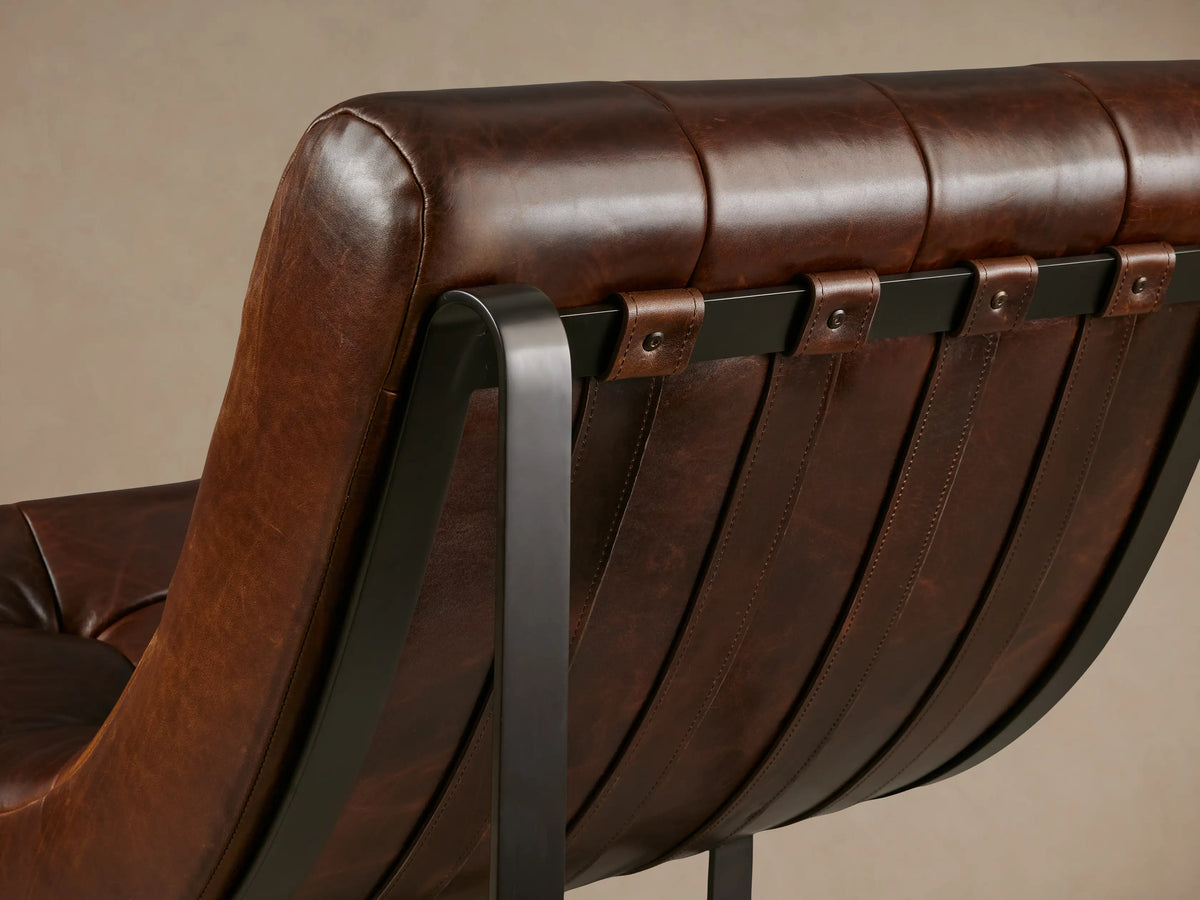 Front view of a Callaway Chair with brown tufted leather upholstery and black metal legs, on a wooden floor against a beige wall.