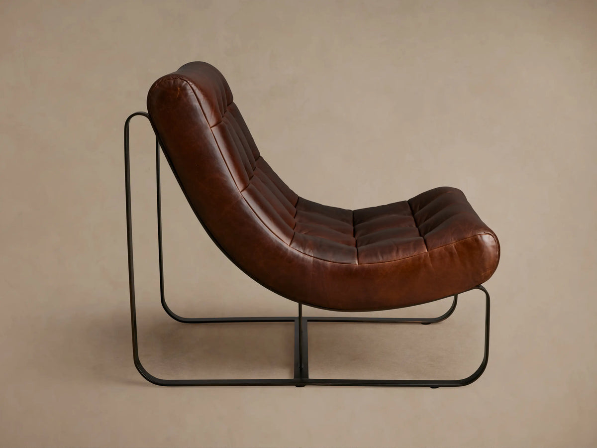 Brown leather Callaway chair with tufted seat and backrest. Curved design on black metal frame, viewed from an angle against a neutral background.