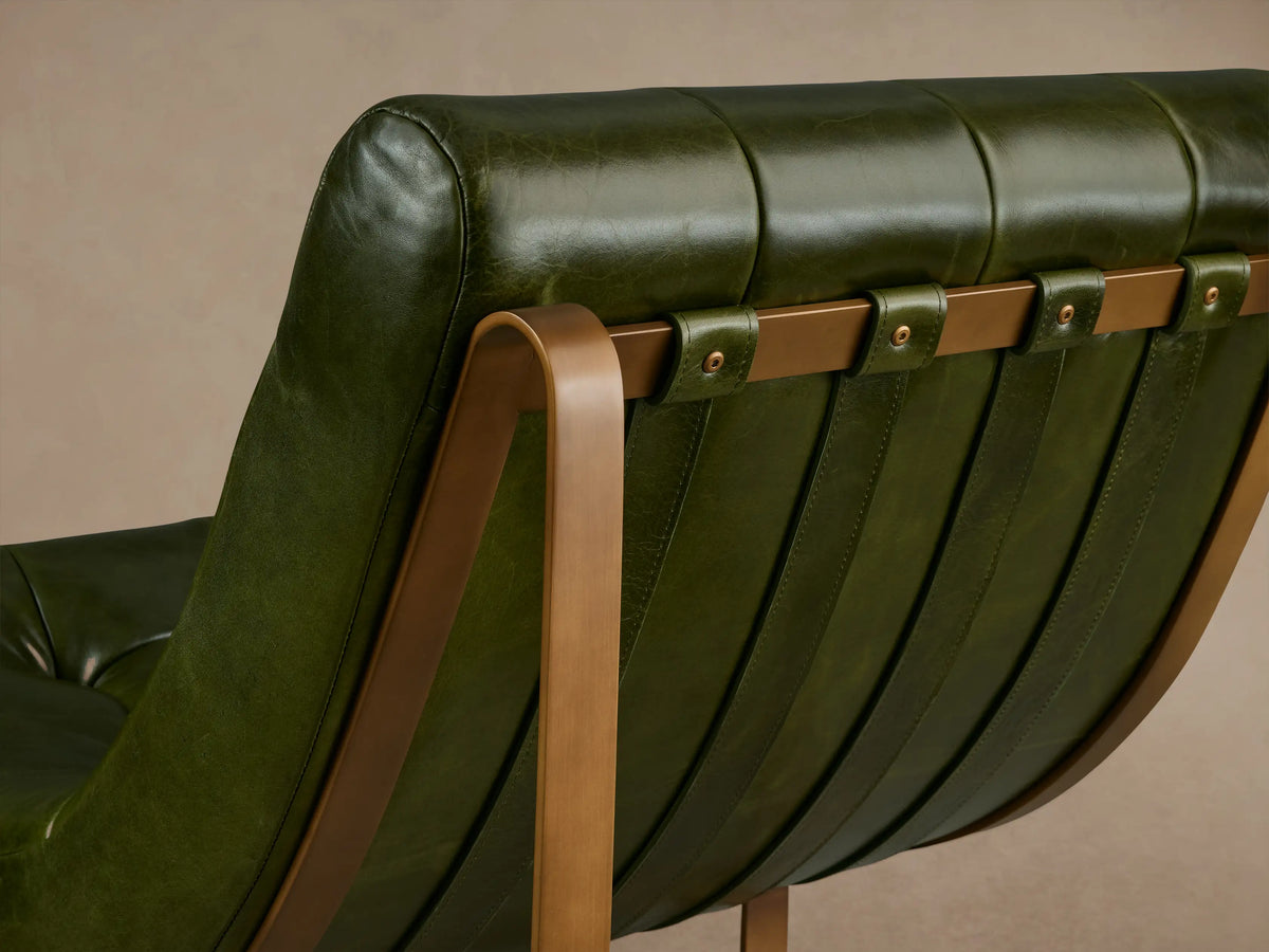 Olive green leather Callaway Chair with a tufted backrest and seat, supported by sleek wooden legs on a wooden floor.