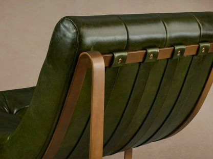 Olive green leather Callaway Chair with a tufted backrest and seat, supported by sleek wooden legs on a wooden floor.