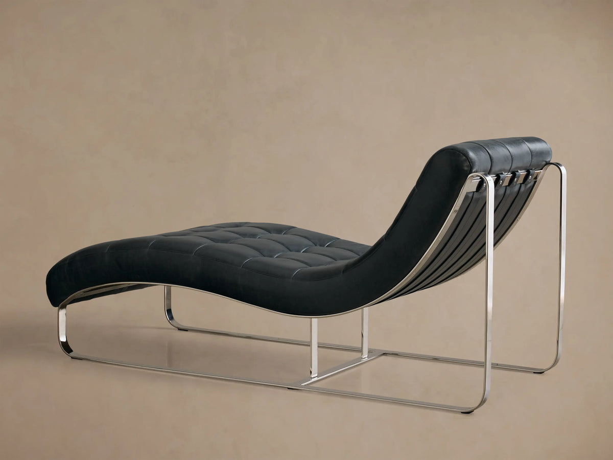 Side view of the charcoal blue leather Callaway Leather Chaise, showing the tufted seat and polished metal frame.