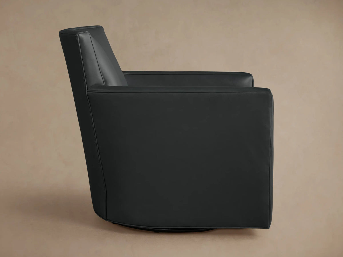 Dark charcoal Rudy Leather Swivel Chair, angled back view, high back, subtly curved arm, on a light brown studio background.