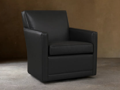 Black leather Rudy Swivel Chair with a modern, clean design, square arms, shown on a wooden floor against a light wall.