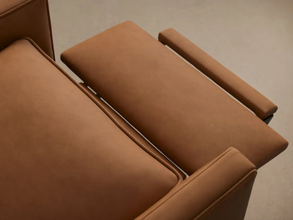 Front view of a warm brown leather Rudy Swivel Recliner with padded arms & cushions, on a black swivel base on wood floor.