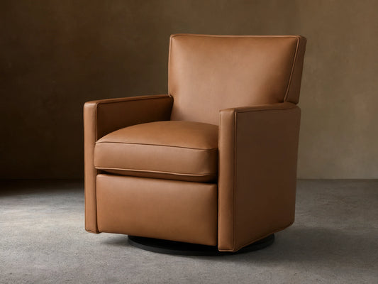 Tan leather Rudy swivel recliner, square arms & back, with a plump seat cushion, on a dark round swivel base, on wood floor.