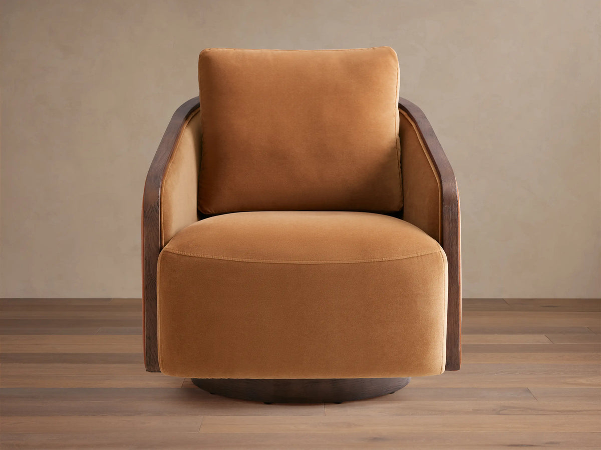 Angled front view of the beige Pomona Swivel Chair with dark wood accents and exposed oak edges on the arms and swivel base.