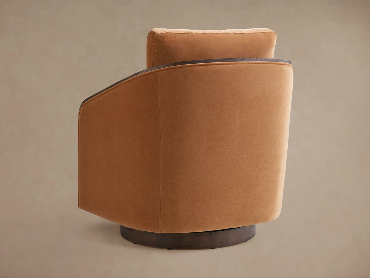 Pomona Swivel Chair: Amber upholstered chair with dark curved oak arms and a round swivel base, front view on wood floor.