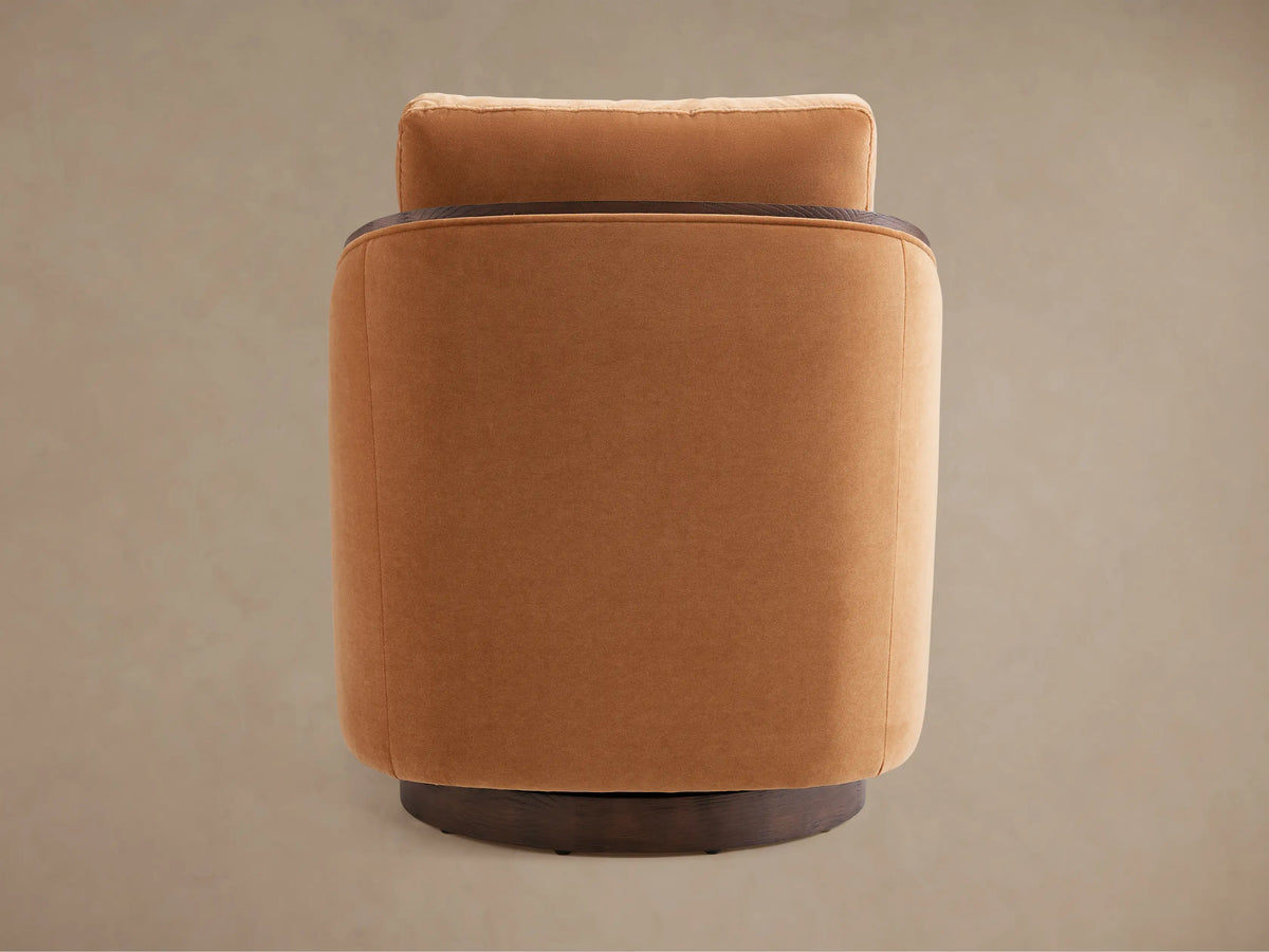 Close-up of Pomona Swivel Chair, featuring soft camel fabric upholstery and dark exposed oak arms.