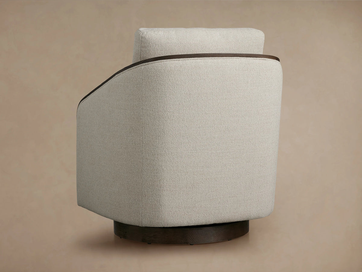 Pomona Swivel Chair with soft, light fabric cushions, dark exposed oak arm edges, and curved design. Close-up view.