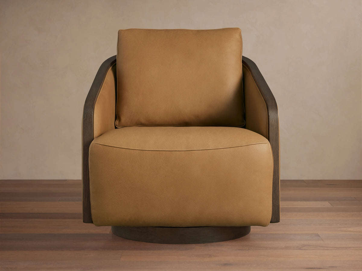 Pomona Leather Swivel Chair in caramel brown leather, featuring oak edges and round base on wooden floor, angled to the right.