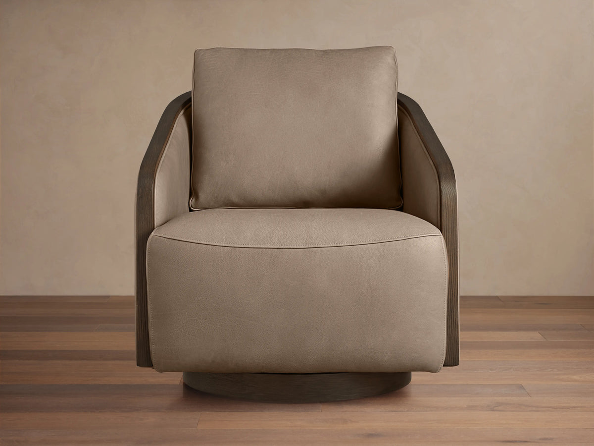 Pomona Leather Swivel Chair in light brown leather with exposed oak edges, featuring a plush seat and back cushion on a wooden floor.