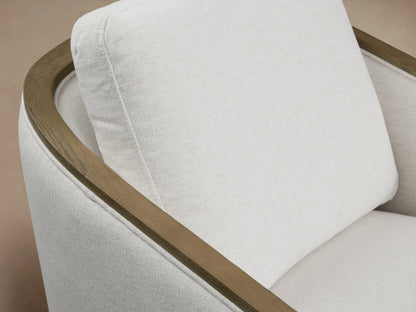 Pomona Swivel Chair in soft, light fabric with exposed oak edges on arms and base, viewed from the front on hardwood floor.