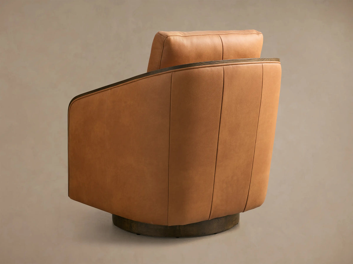 Rear view of a Cognac Pomona Leather Swivel Chair with dark oak arm edges and a circular swivel base.