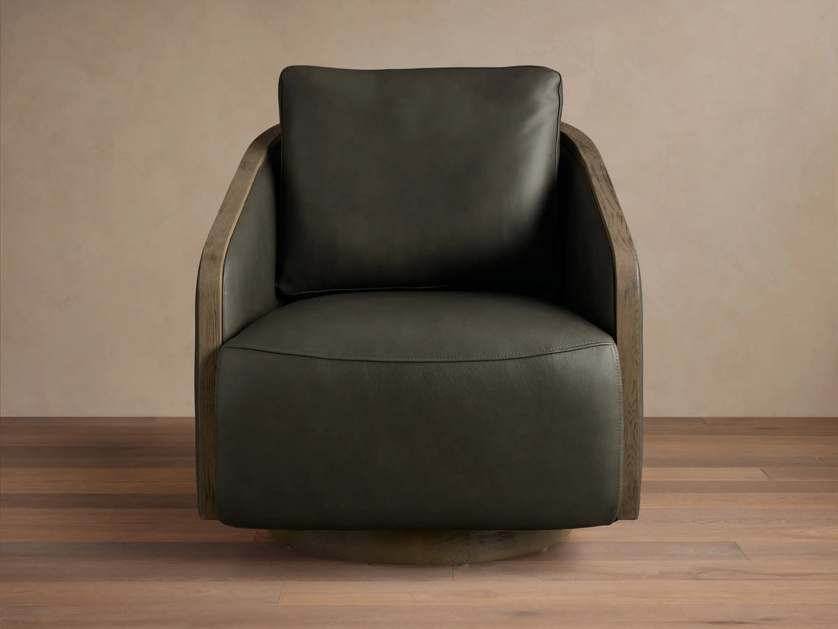 Front view of the dark olive green leather Pomona Leather Swivel Chair with exposed oak arms and a round swivel base.
