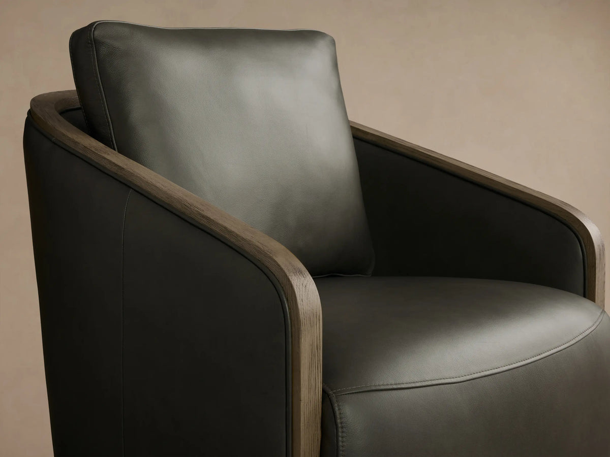 Front view of the dark olive Pomona Leather Swivel Chair with exposed oak edges on the arms and round swivel base.
