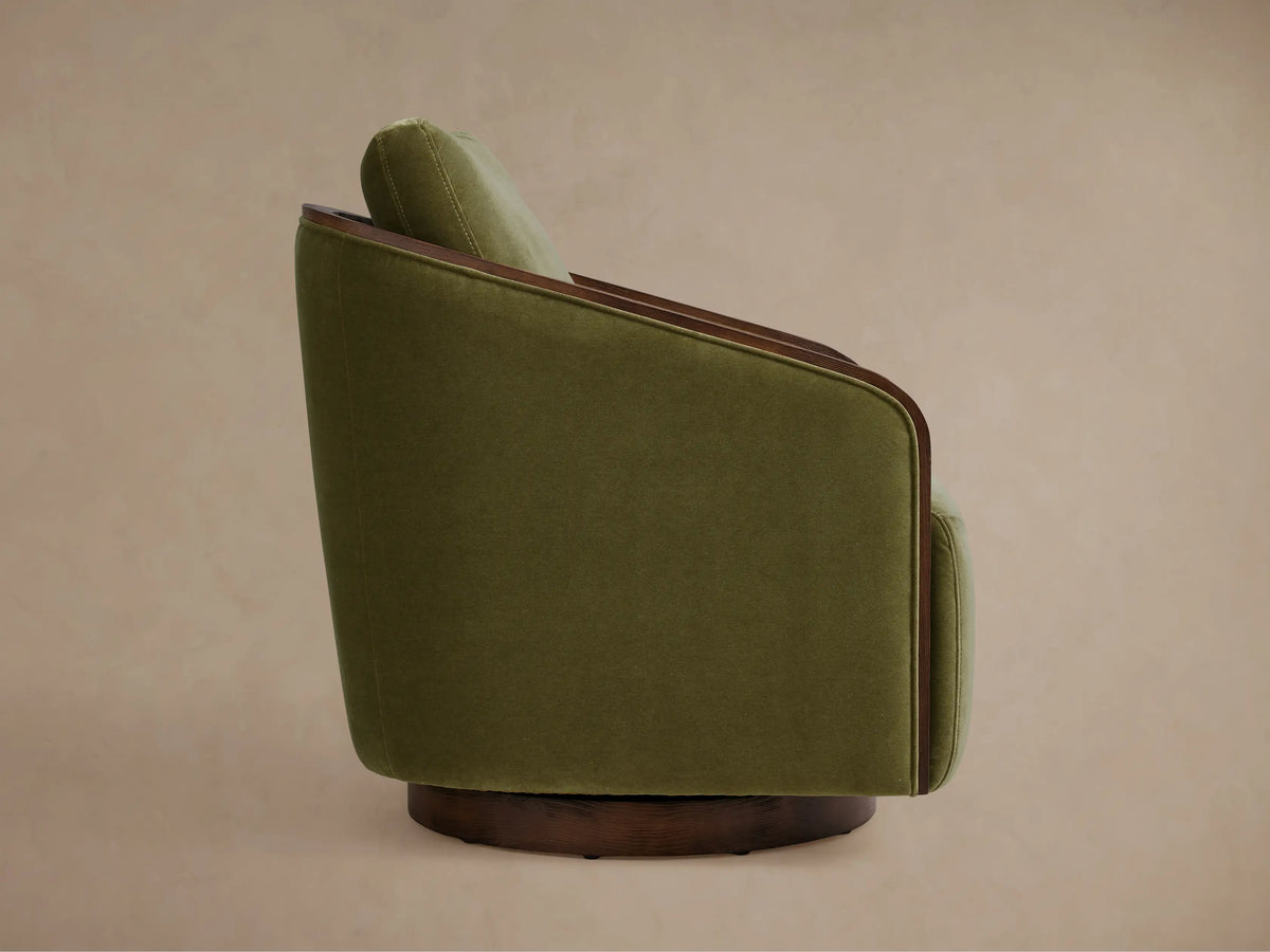 Pomona Swivel Chair in green fabric with exposed oak arm and base edges. Features plush cushions, set against a neutral background.