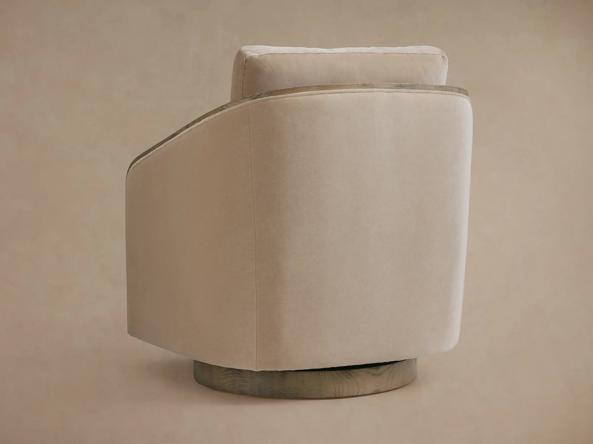 Pomona Swivel Chair in a side view, featuring neutral beige fabric, exposed oak edges, and a solid base. Soft cushions visible.