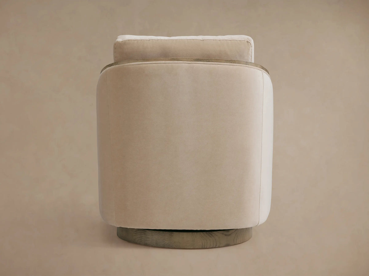Pomona Swivel Chair in soft beige fabric, viewed from the side. Features exposed oak edges and round swivel base.