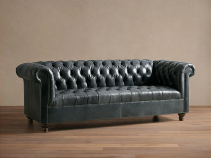Front view of the dark blue-gray Berwick Leather Sofa, featuring a button-tufted back, rolled arms, and carved walnut legs.