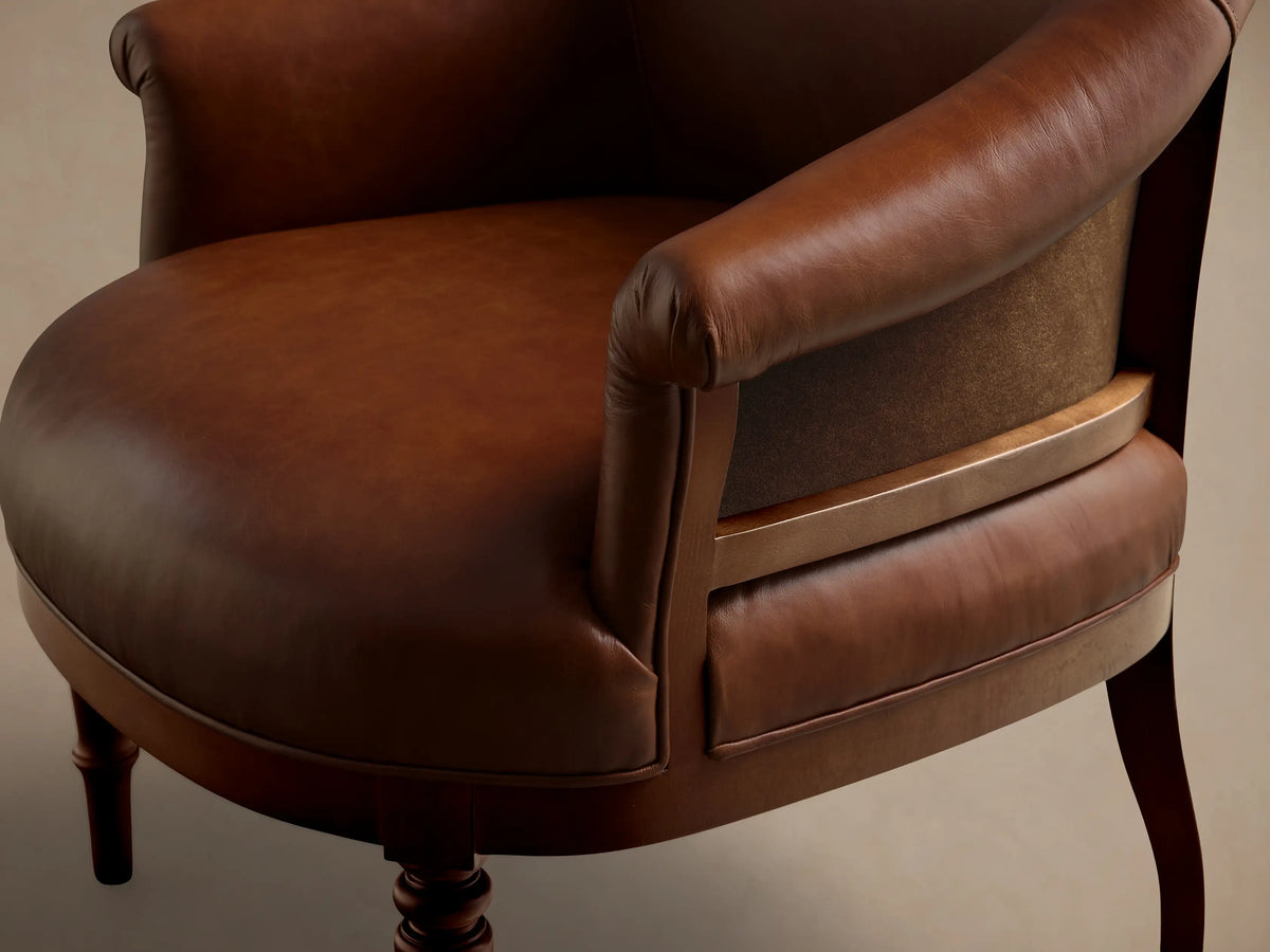 Close-up of the brown Polly Leather Chair, showing the smooth leather, curved armrest, and hand-turned wooden leg details.
