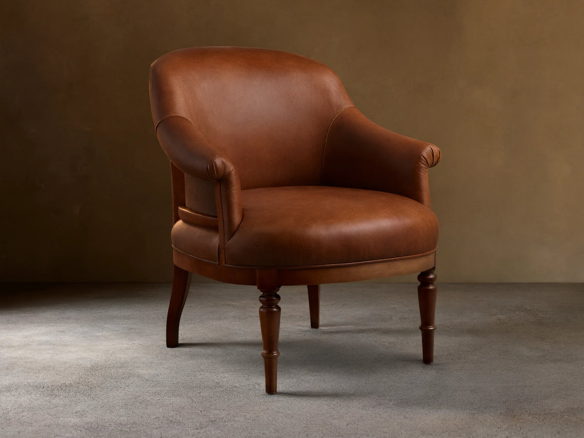 Front view of a brown leather Polly Leather Chair with rolled arms and hand-turned dark wood legs.