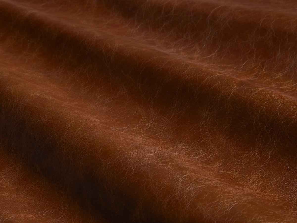 Rear view of the brown Polly Leather Chair, featuring a curved leather back, exposed wooden frame, and turned legs.