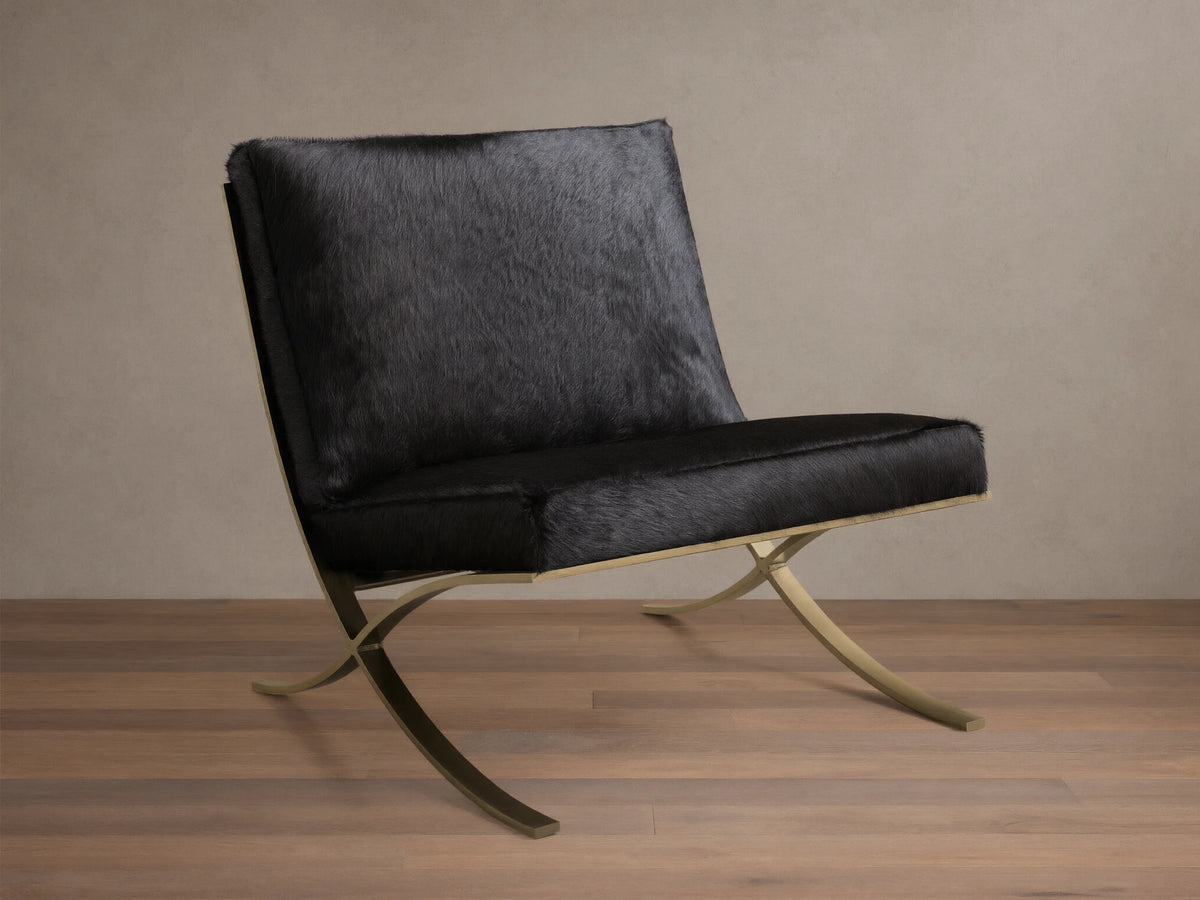 Front view of the black Moxie Hair on Hide Chair, featuring gold-toned X-shaped stainless steel legs.