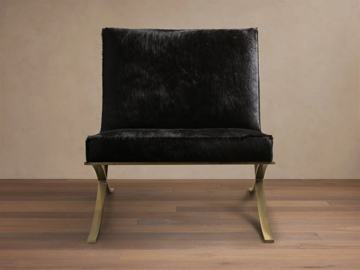 Front view of the black Moxie Hair on Hide Chair, featuring gold-toned X-shaped stainless steel legs.