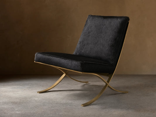 Front view of the black Moxie Hair on Hide Chair, featuring gold-toned X-shaped stainless steel legs.