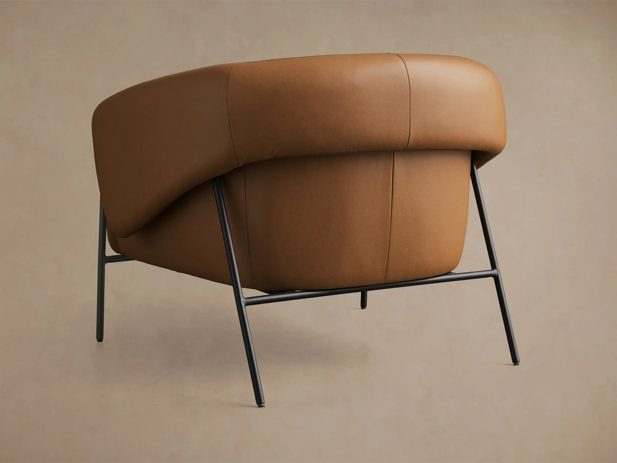 Close-up of the tan leather armrest and seat of the Linus Leather Chair, featuring detailed stitching.