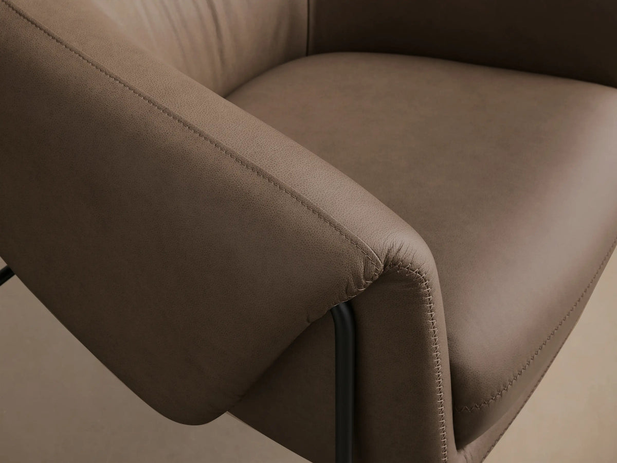 Front view of a taupe Linus Leather Chair, featuring a rounded silhouette, detailed stitching, and black metal frame legs.