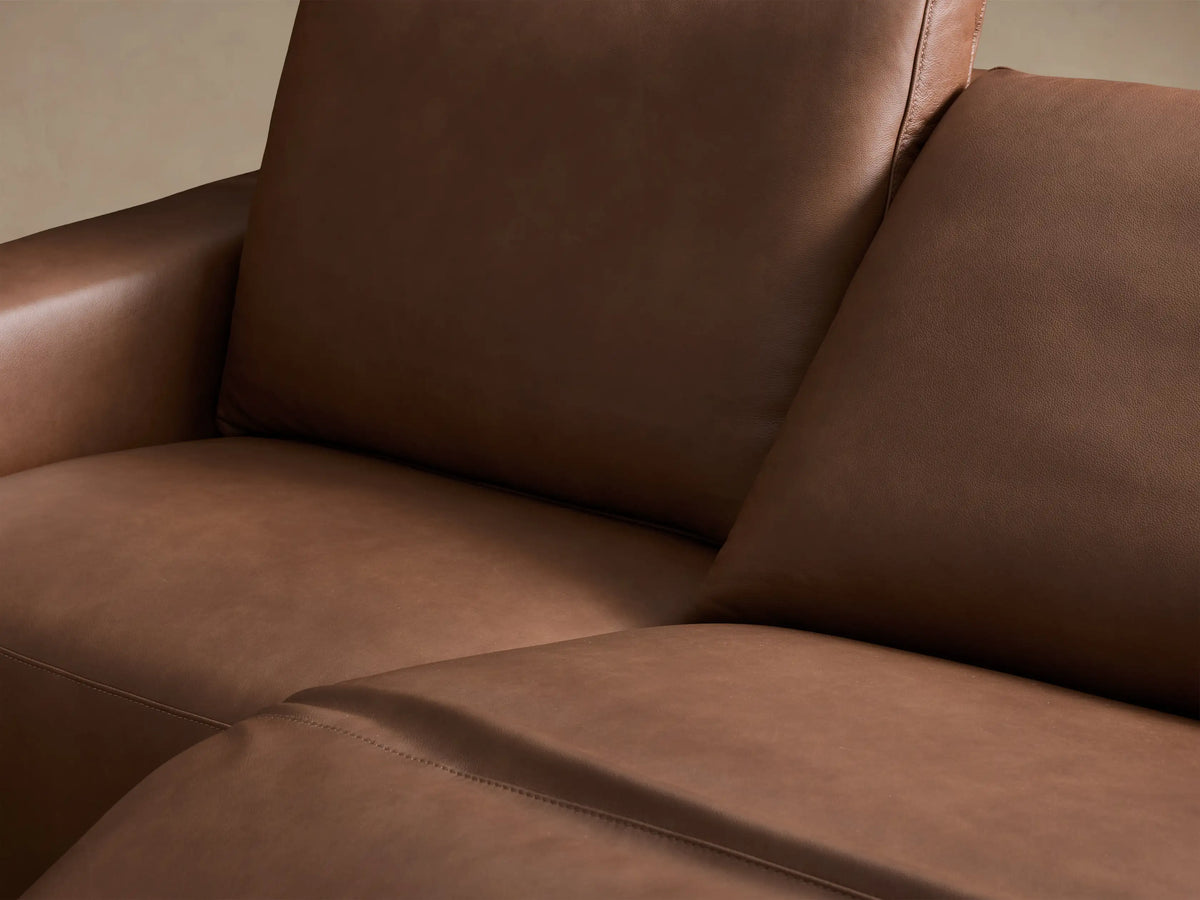 Front view of the brown Brennan Leather Two-Piece Motion Sofa, featuring two distinct reclining seats and wide armrests.