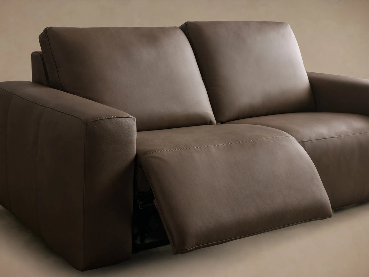Close-up of brown Brennan Leather Two-Piece Motion Sofa with two black motion control buttons, white stitching, and zipper.