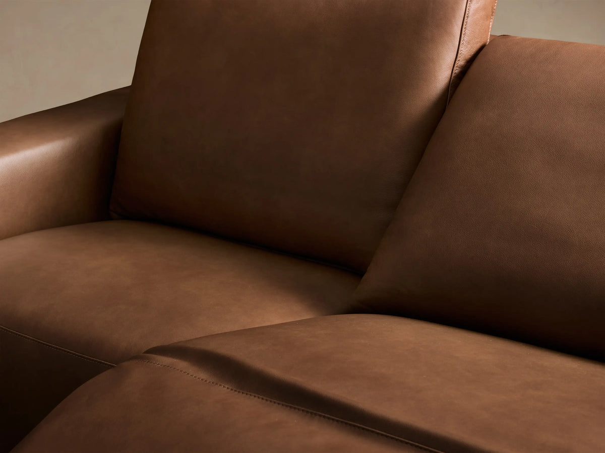 Close-up of the two black oval motion controls embedded in the brown leather of the Brennan™ Leather Three-Piece Motion Sofa.