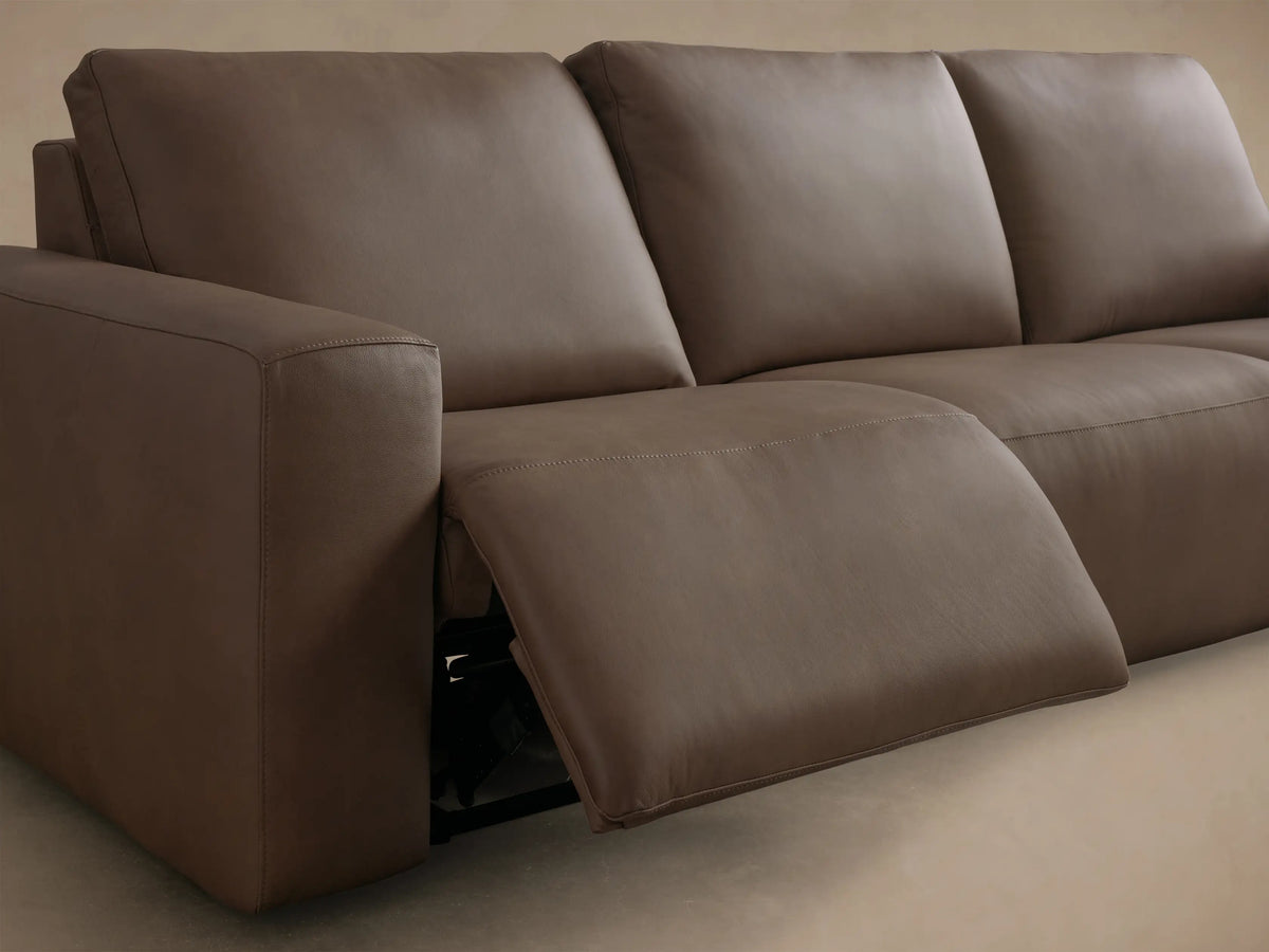 Close-up of the brown pebbled leather upholstery and two black motion control buttons on the Brennan Leather Three-Piece Motion Sofa.