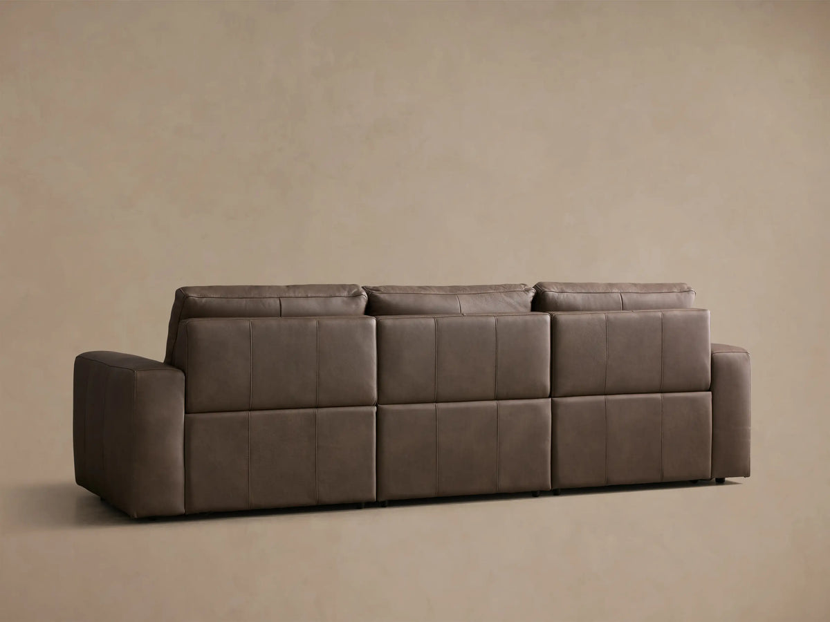 Close-up of a brown Brennan Leather Three-Piece Motion Sofa™ with the footrest extended on the left recliner.